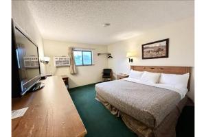 a hotel room with a bed and a flat screen tv at Homestead Inn Wolf Point Hwy 2 in Wolf Point