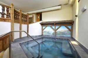 a swimming pool in a house with a window at Hotel Villa Fosine Spa & Wellness in Pinzolo