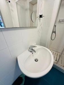 Un lavabo blanco en un baño con espejo. en Luminoso appartamento con garage privato gratuito, en Milán