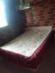 a bed in a room with a brick wall at chalé em Tamandaré in Tamandaré