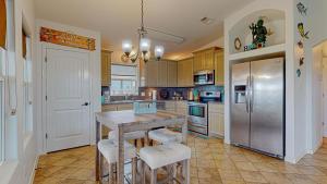 a kitchen with a table and a stainless steel refrigerator at Casa Siwichi in Crystal Beach
