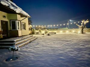 a snow covered yard next to a house with lights at Agroturystyka Gorajeckie Roztocze in Górajec Zastawie