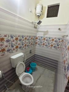 een badkamer met een toilet en bloemen aan de muur bij Fort View Palace in Jodhpur +18 foto's