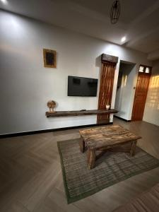 un soggiorno con un tavolo e una TV a parete di Cj VILLA a Karatu