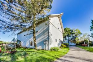 a white barn with a tree next to a road at Berrywood Loft in Lakeside