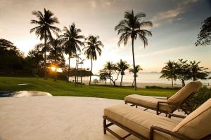 um pátio com duas cadeiras e palmeiras e o oceano em Spectacular Mediterranean-Style Mansion with Beachfront Views in Playa Flamingo em Playa Flamingo