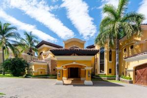 uma grande casa amarela com palmeiras na entrada da garagem em Spectacular Mediterranean-Style Mansion with Beachfront Views in Playa Flamingo em Playa Flamingo mais 48 fotografias