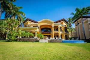 uma grande casa amarela com palmeiras em frente em Spectacular Mediterranean-Style Mansion with Beachfront Views in Playa Flamingo em Playa Flamingo