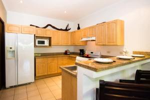 a kitchen with wooden cabinets and a white refrigerator at Beautiful Condo in Peaceful Cliffside Location with a Private Balcony & Stunning Ocean and Mountain Views in Playa Flamingo +22 photos