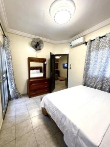 a bedroom with a white bed and a mirror at Yoff Oasis Duplex in Dakar