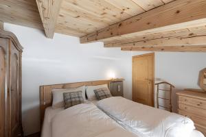 una camera da letto con letto, lenzuola bianche e soffitti in legno di Mansarda di charm Valli di Borzago a Mortaso
