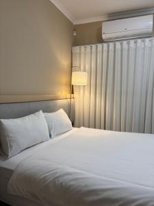 una camera da letto con un letto bianco e una finestra di The Oryx Luxury Apartment a Windhoek
