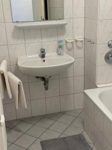 ein weißes Badezimmer mit Waschbecken und Badewanne in der Unterkunft MonoApartment in Frankfurt am Main