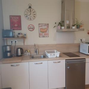 a kitchen with a sink and a clock on the wall at Apt cosy dans maison de charme in La Rochelle