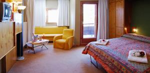 una stanza d'albergo con un letto e una sedia gialla di Eurotel Cermis a Cavalese