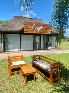 two benches and a table in front of a building at Termas Concepcion in Concepción del Uruguay