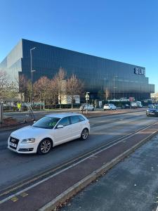 um carro branco está dirigindo por uma rua da cidade em Hendham House em Manchester