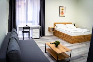 a bedroom with a bed and a couch and a table at Urban76 Apartments in Târgu-Mureş