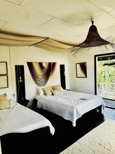 a bedroom with two beds and a large window at Chinuk Boutique Hotel in Puerto Viejo