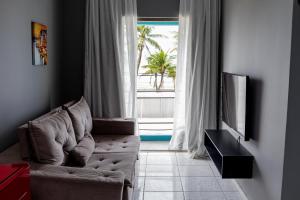 a living room with a couch in front of a window at Santa Helena Pousada in Guarujá