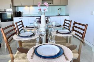 a dining room table with plates and glasses on it at Superb penthouse swimming pools equipped solarium panoramic view in Xeresa