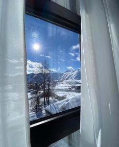 una ventana con vistas a las montañas cubiertas de nieve en Hotel Qumli Apartment with mountain views, en Kʼumlistsʼikhe