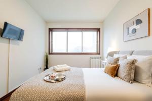 a white bedroom with a bed with a tray on it at Modern & Spacious Flat with Garage by HostWise in Vila Nova de Gaia +28 photos
