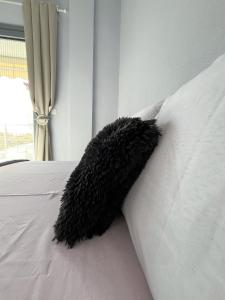 a black pillow on a white bed with a window at Elenis House in Leptokaria