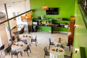 a restaurant with tables and chairs and a green wall at Santa Helena Pousada in Guarujá