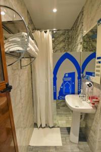 un baño con lavabo y ducha en Hotel Dar Annasr, en Chefchaouen