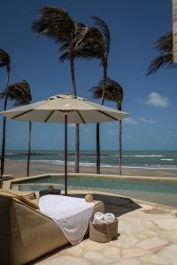 a couch with an umbrella next to the beach at Lahaina Hotel in Amontada