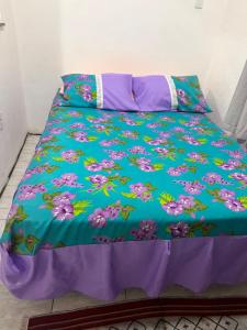 a bed with a blue comforter with flowers on it at Flat Serra Grande in Viçosa do Ceará