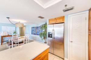 Una cocina con refrigerador de acero inoxidable y una mesa. en Beachfront Condo Sleeps 10 Heated Pool - 307, en St Pete Beach