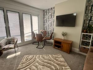 a living room with a flat screen tv and chairs at SeaScape in Bexhill