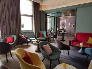 a lobby with chairs and tables and a mirror at The Chapter Hotels -Lancaster Gate in London