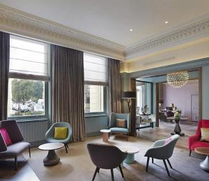 a living room with chairs and tables and windows at The Chapter Hotels -Lancaster Gate in London