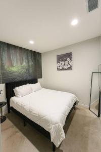a bedroom with a white bed with a painting on the wall at Forestline Suite in Des Moines