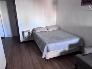 a small bed in a small room with wood floors at Carnatal Agora- 30m da Arena das Dunnas in Natal