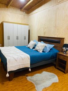 una camera da letto con un letto con lenzuola e cuscini blu di Cabañas con Tinajas Mahuidas Panguipulli a Panguipulli