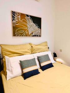 un letto con tre cuscini e un dipinto sul muro di Sunny house by the sea a Taʼ Xbiex
