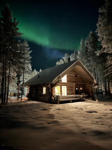 a log cabin with the aurora in the sky at Aurora Forest Lodge Ylläs in Äkäslompolo