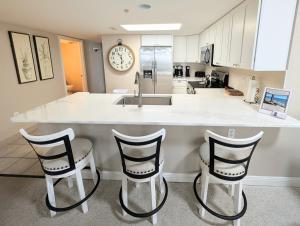 a kitchen with a counter with three chairs and a sink at Beautiful Beachfront 2BR2Bath & 2 Balconies in North Myrtle Beach