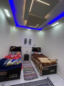 Dos camas en una habitación con techo azul. en family home, en Siwa