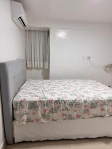 ein Schlafzimmer mit einem Bett mit geblümter Tagesdecke in der Unterkunft Cobertura pé na areia com piscina exclusiva única in João Pessoa