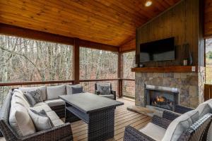 porche cubierto con sofá y chimenea en Overlook Nook at Eagles Nest, en Elk Park