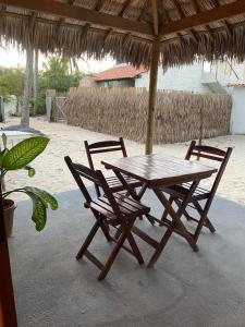a picnic table and two chairs under a straw umbrella at Casa Juba in Camocim