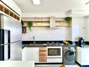 a white kitchen with a stove and a refrigerator at Apto Penha a 300M PRAIA 8 min do BETO CARREIRO com PISICNA, sacada com CHURRASQUEIRA privativa, AR CONDICIONADO Wi Fi, PORTARIA 24h,vaga privativa de GARAGEM in Penha +23 photos