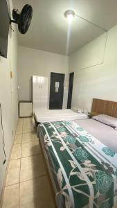 um quarto com uma cama coberta com um cobertor verde e branco em Hotel Colombo em São Lourenço