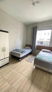 um quarto com duas camas e uma janela em Hotel Colombo em São Lourenço