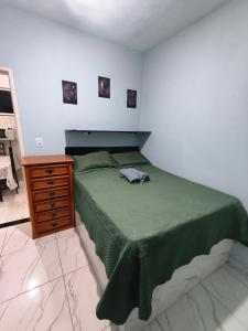 a bedroom with a green bed and a wooden dresser at Recanto do Coral in Cabo Frio